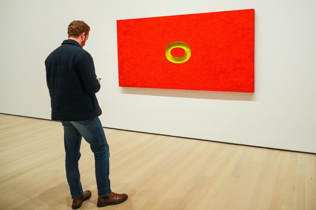 a red painting on the wall with a yellow oval on the middle